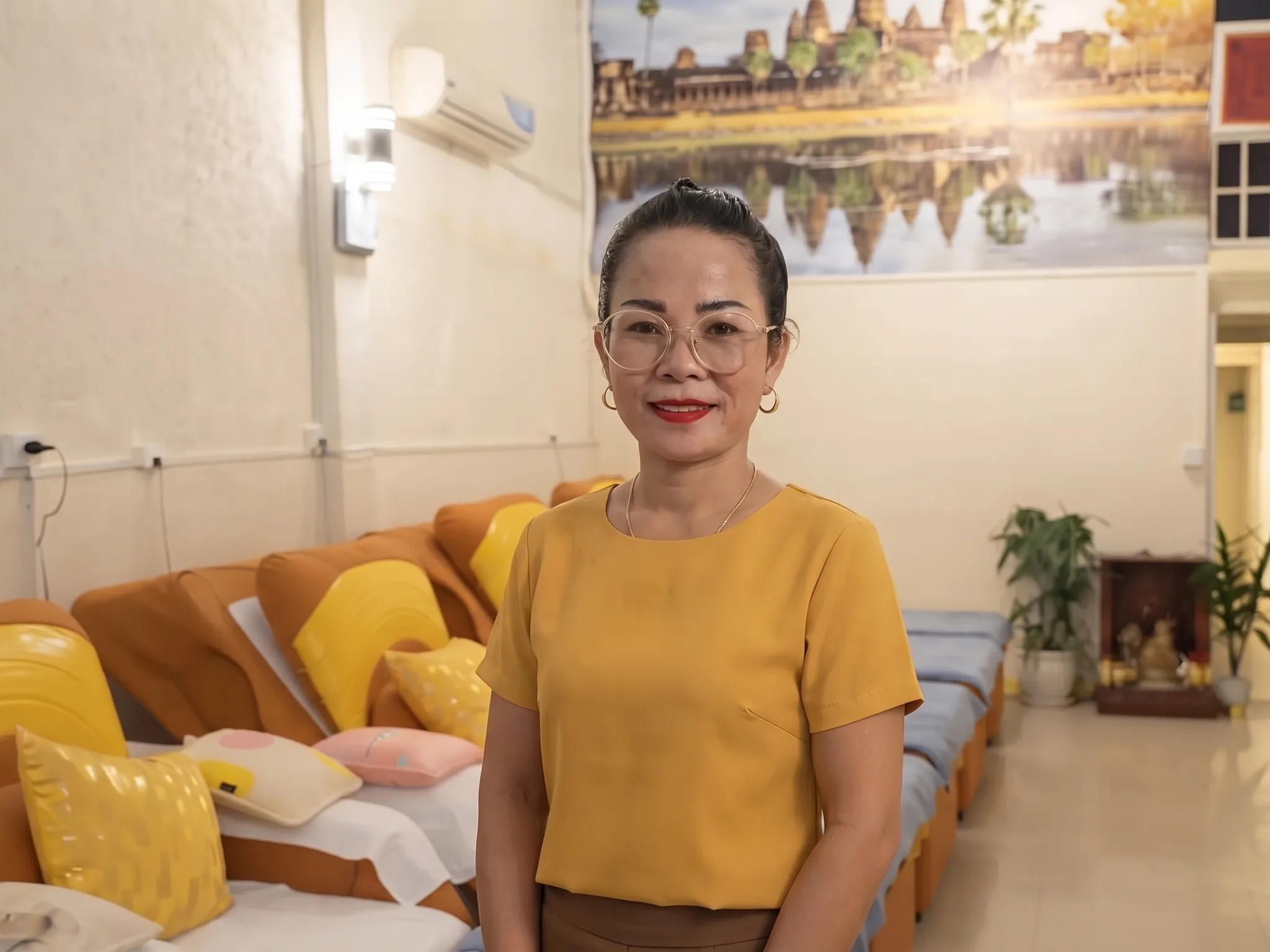 The owner of Amiga Massage and Spa, standing in the salon in front of the Angkor Wat mural