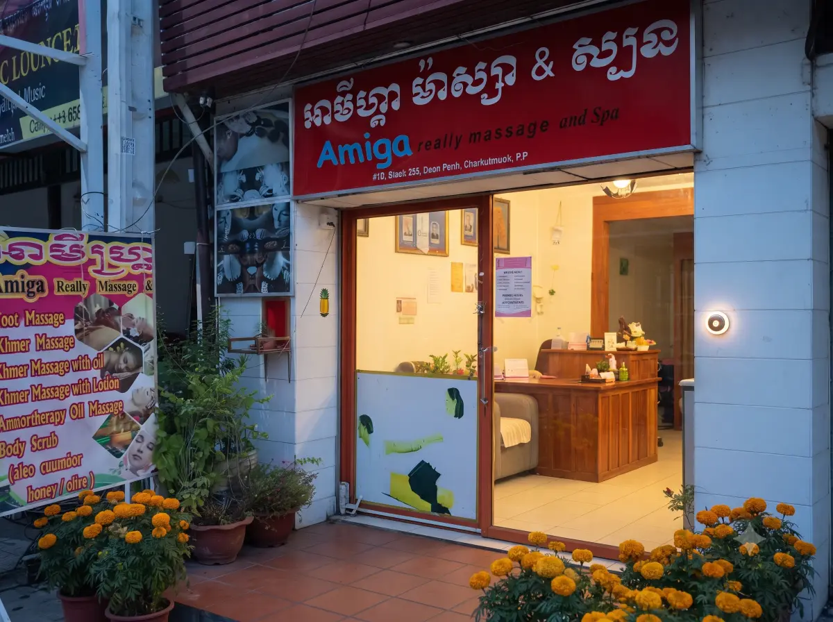 The lit shopfront of Amiga at dusk, its glass door open on the reception desk, with potted marigolds on the pavement